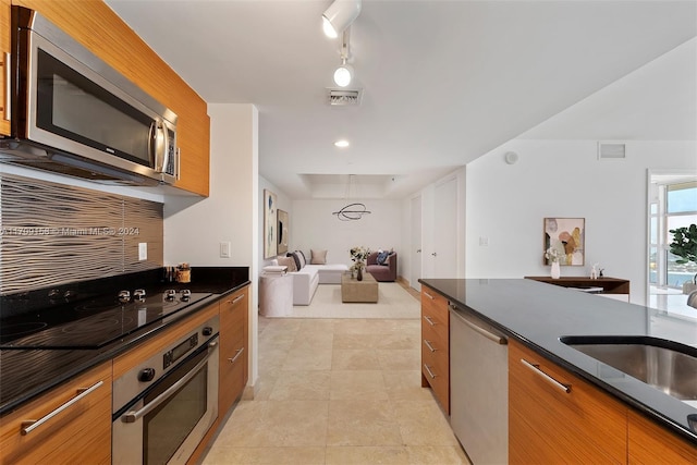 kitchen featuring appliances with stainless steel finishes, light tile patterned floors, dark stone countertops, and sink