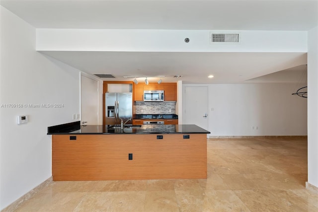 kitchen featuring kitchen peninsula, appliances with stainless steel finishes, backsplash, and sink