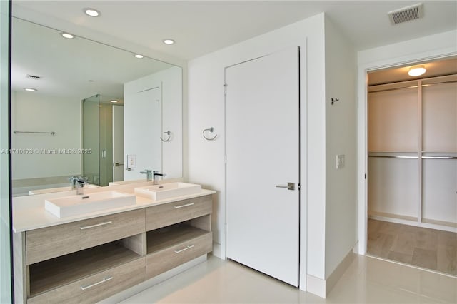 bathroom with a shower with door, tile patterned floors, and vanity