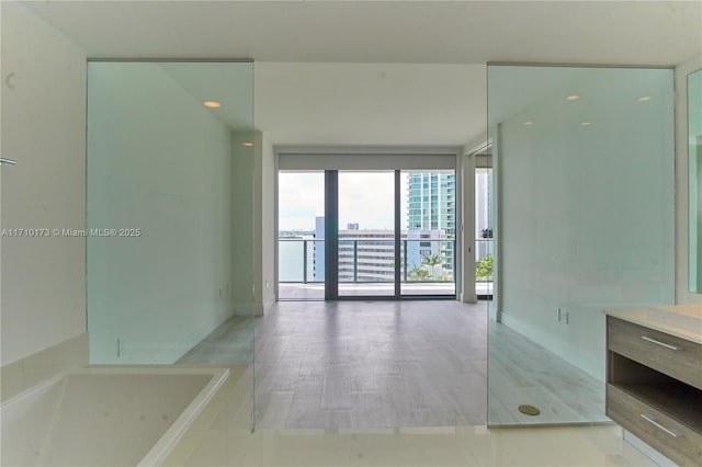 bathroom with vanity, floor to ceiling windows, and a bath