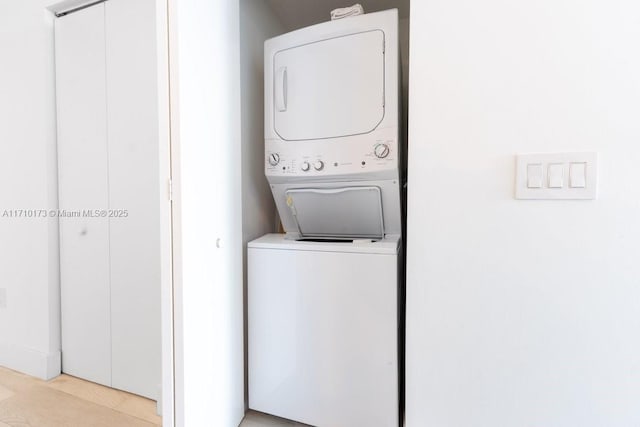 laundry area with stacked washer / dryer and light hardwood / wood-style flooring