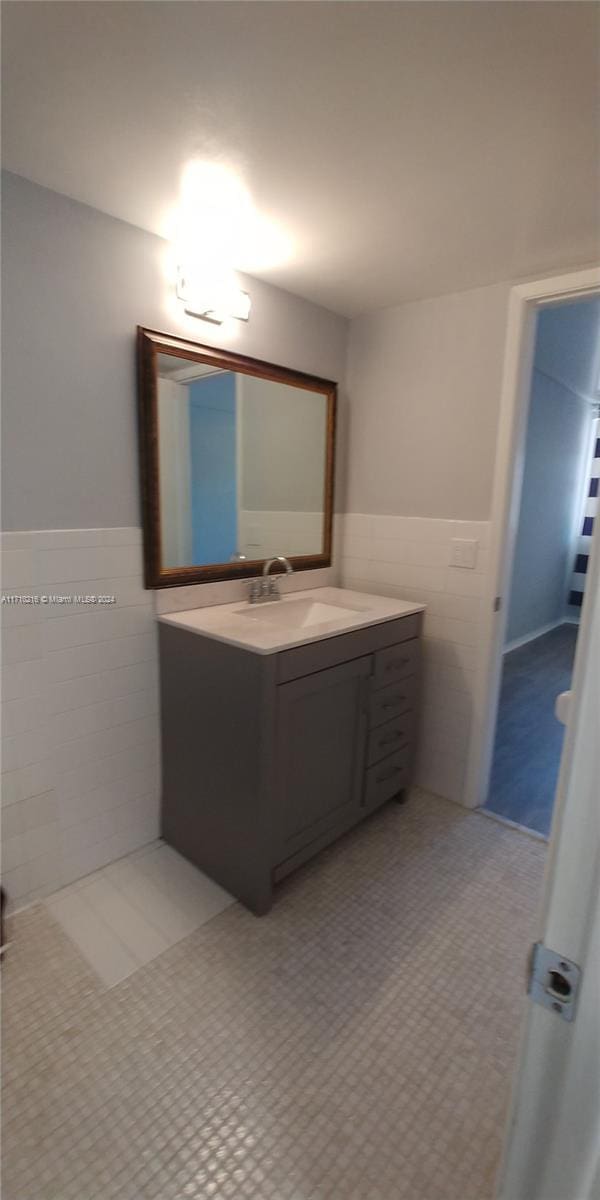 bathroom with tile patterned flooring, vanity, and tile walls