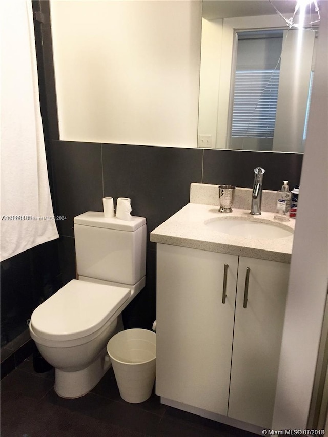 bathroom featuring tile patterned flooring, vanity, tile walls, and toilet