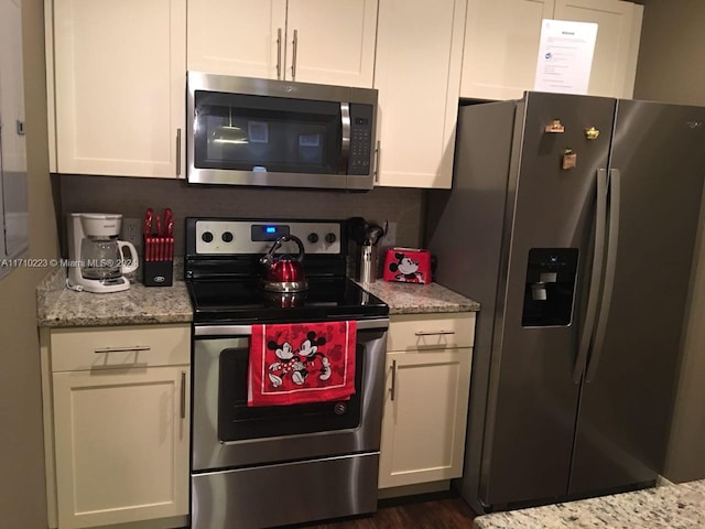 kitchen with light stone counters, white cabinetry, dark wood-type flooring, and appliances with stainless steel finishes