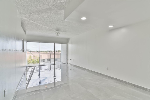 unfurnished room with ceiling fan and a textured ceiling