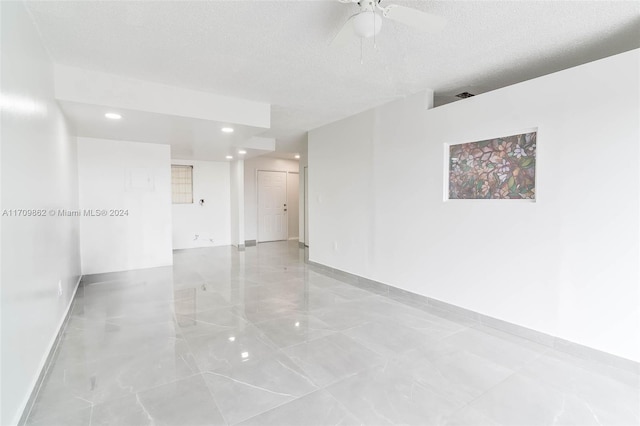 empty room with a textured ceiling and ceiling fan