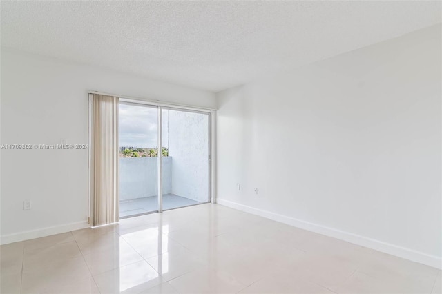 spare room with a textured ceiling and light tile patterned flooring