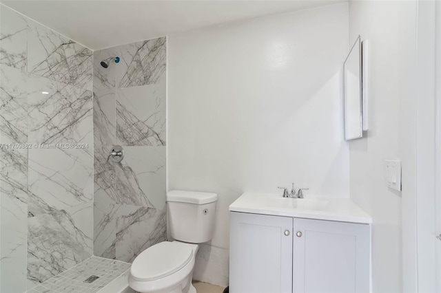 bathroom with a tile shower, vanity, and toilet