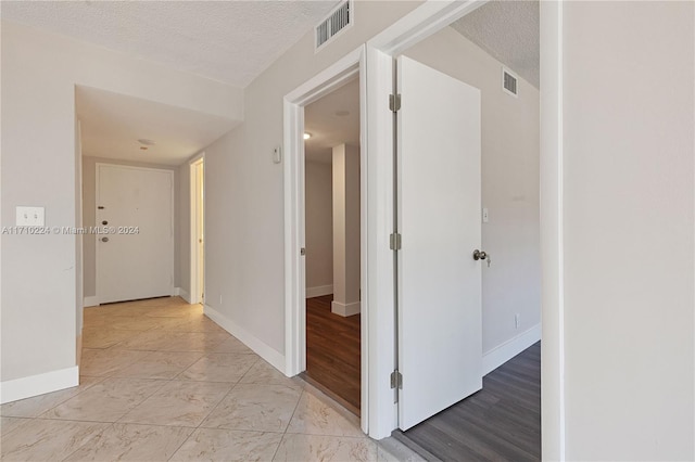 hallway featuring a textured ceiling and light wood-type flooring