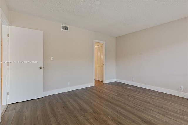 unfurnished room with a textured ceiling and dark hardwood / wood-style floors