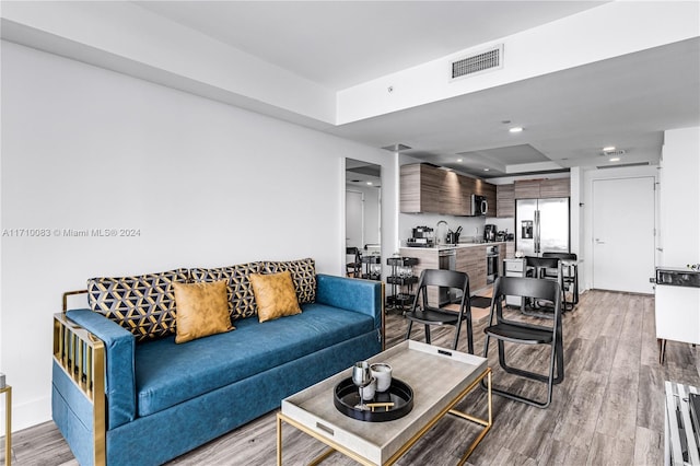 living room featuring a tray ceiling and light hardwood / wood-style flooring