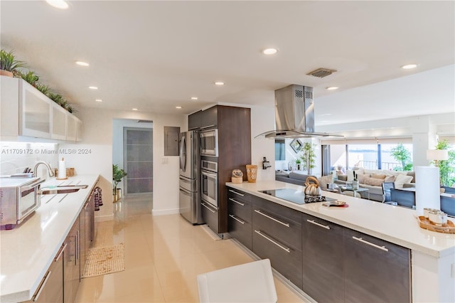 kitchen with sink, light tile patterned floors, dark brown cabinets, island exhaust hood, and stainless steel appliances