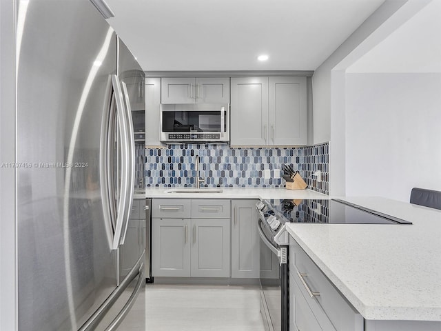 kitchen with backsplash, gray cabinets, sink, and appliances with stainless steel finishes