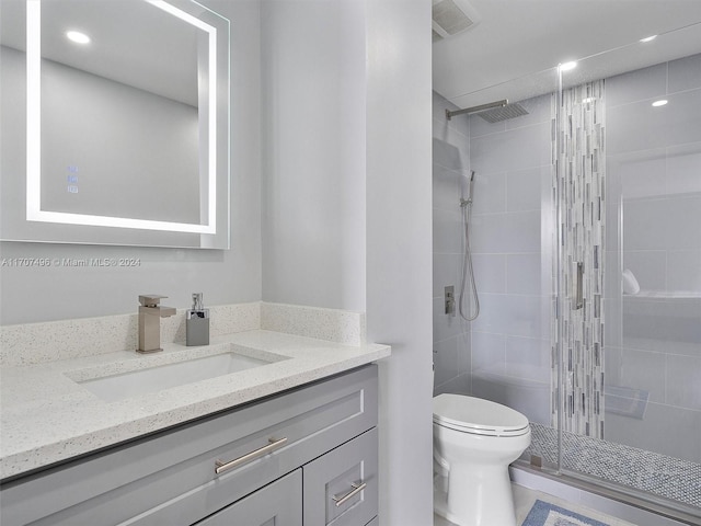 bathroom featuring tile patterned floors, a shower with door, vanity, and toilet