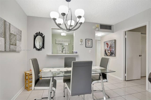 dining area with sink, light tile patterned floors, a textured ceiling, and an inviting chandelier