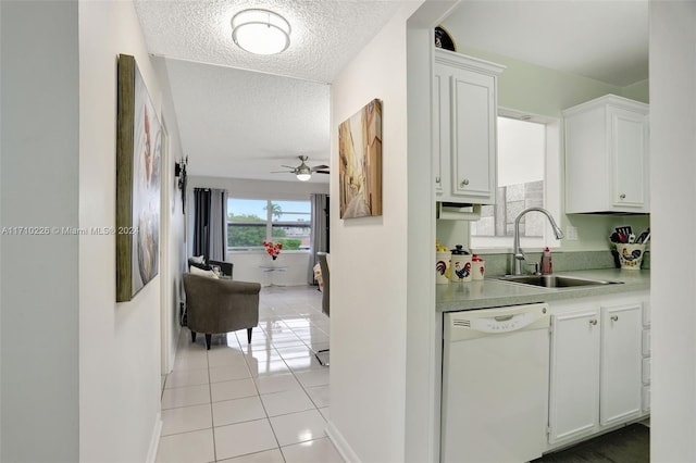 kitchen with a textured ceiling, white dishwasher, sink, light tile patterned floors, and white cabinets