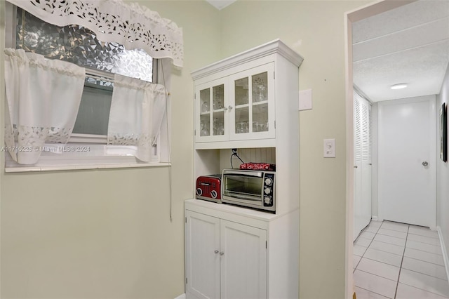 kitchen featuring light tile patterned floors, a textured ceiling, and white cabinetry