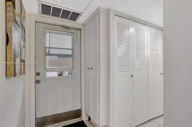 doorway featuring light tile patterned flooring and a textured ceiling