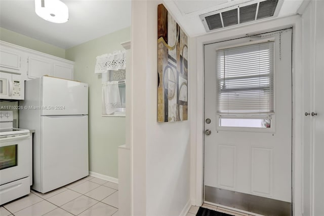 kitchen featuring white cabinetry, light tile patterned flooring, and white appliances