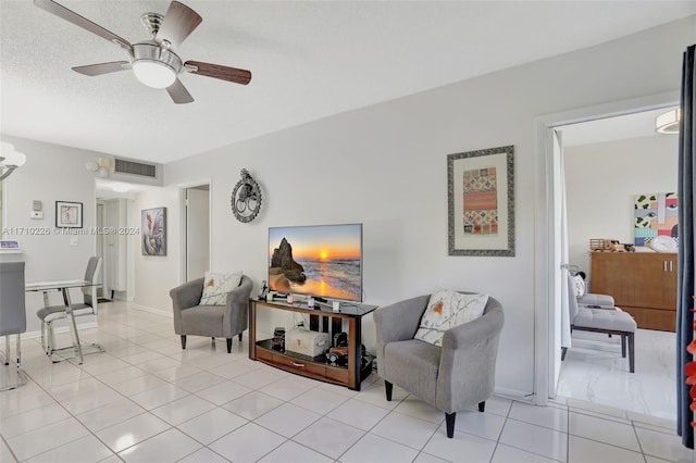 living room featuring ceiling fan, light tile patterned flooring, and a textured ceiling