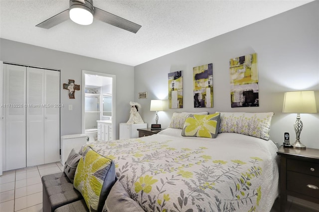 bedroom featuring ensuite bath, ceiling fan, light tile patterned floors, a textured ceiling, and a closet