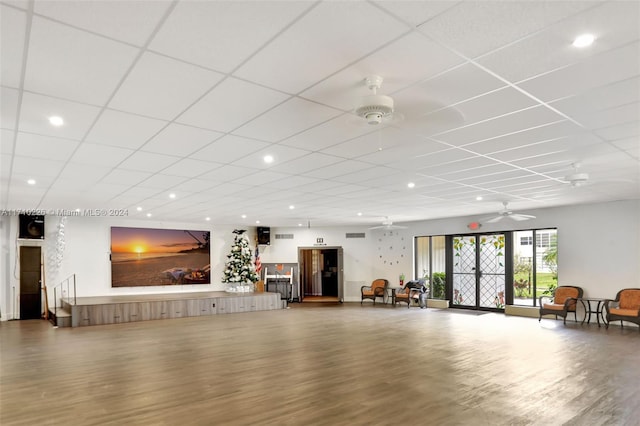 exercise room with ceiling fan, a drop ceiling, and wood-type flooring