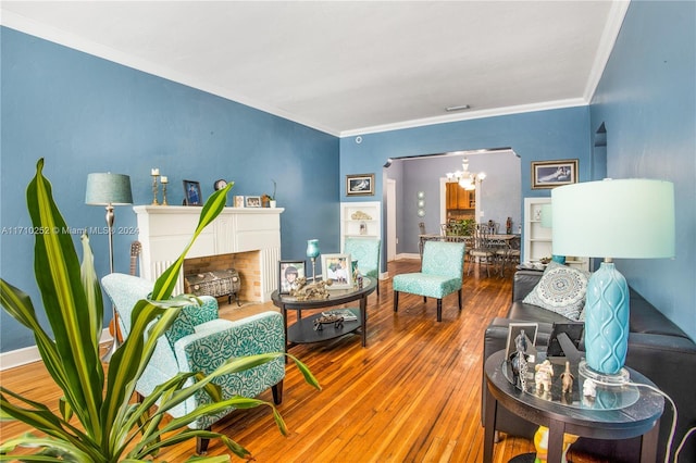 living room with hardwood / wood-style floors, a fireplace, crown molding, and a chandelier