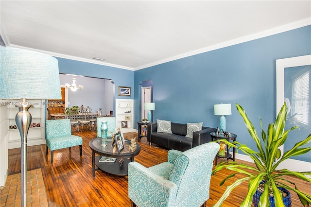 living room featuring crown molding, wood-type flooring, and a notable chandelier