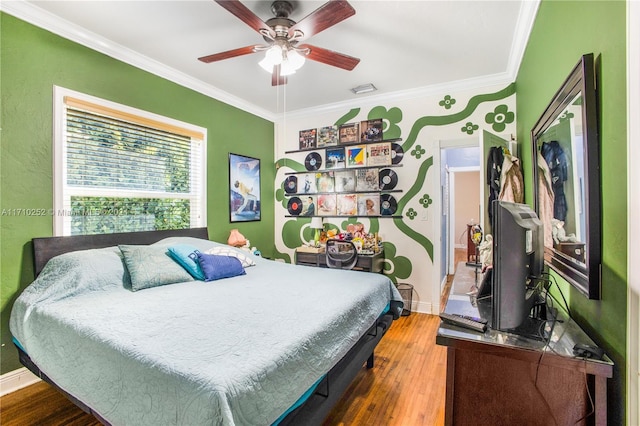 bedroom featuring ceiling fan, wood-type flooring, and ornamental molding