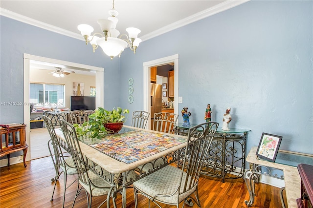 dining space with wood-type flooring, ceiling fan with notable chandelier, and ornamental molding