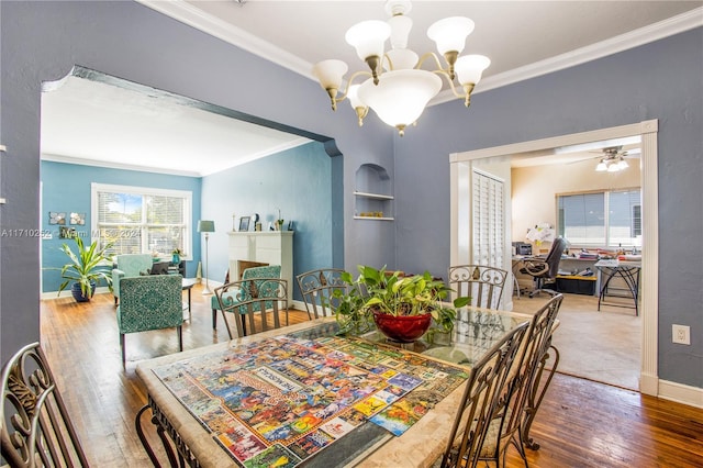 dining room featuring wood-type flooring, ceiling fan with notable chandelier, and crown molding