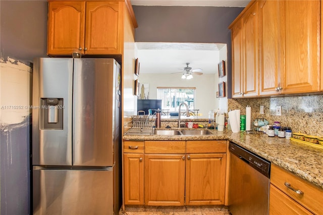 kitchen with light stone countertops, appliances with stainless steel finishes, decorative backsplash, ceiling fan, and sink