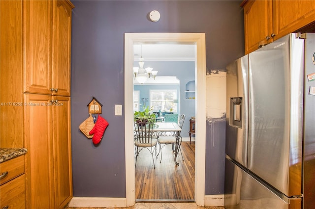 kitchen featuring an inviting chandelier, stainless steel fridge with ice dispenser, light hardwood / wood-style floors, stone countertops, and ornamental molding