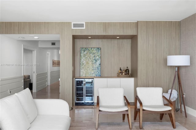 sitting room featuring beverage cooler, visible vents, and a bar