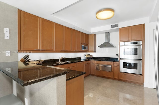 kitchen with visible vents, wall chimney exhaust hood, stainless steel appliances, a sink, and a warming drawer