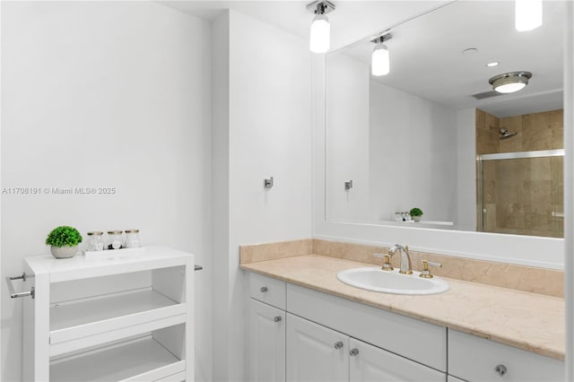 bathroom with visible vents, tiled shower, and vanity