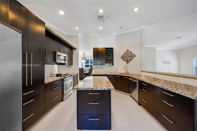 kitchen featuring light stone countertops, a center island, kitchen peninsula, decorative backsplash, and appliances with stainless steel finishes