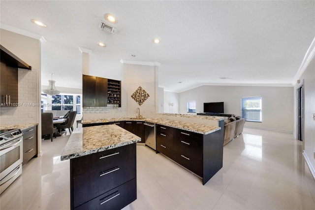 kitchen with kitchen peninsula, backsplash, stainless steel appliances, vaulted ceiling, and a kitchen island