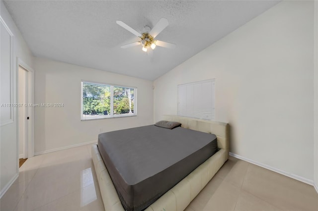 bedroom with light tile patterned floors, a textured ceiling, vaulted ceiling, and ceiling fan