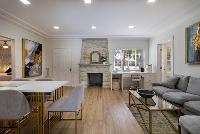 living room featuring light wood-type flooring, a fireplace, and ornamental molding