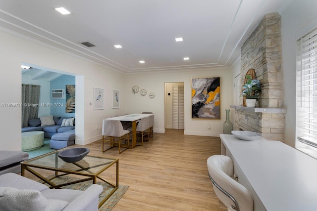 living room with light wood-type flooring, a wall mounted AC, and ornamental molding