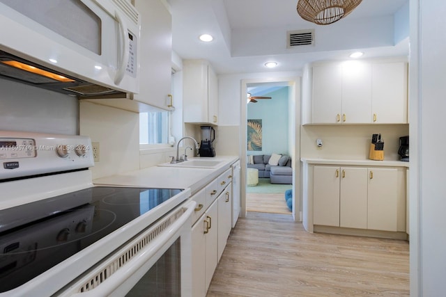 kitchen with white appliances, ceiling fan, sink, light hardwood / wood-style flooring, and white cabinets