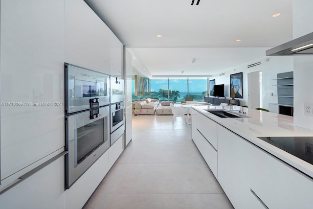 kitchen featuring stainless steel oven, sink, cooktop, extractor fan, and white cabinets