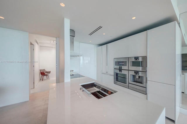 kitchen featuring white cabinetry and wall chimney range hood