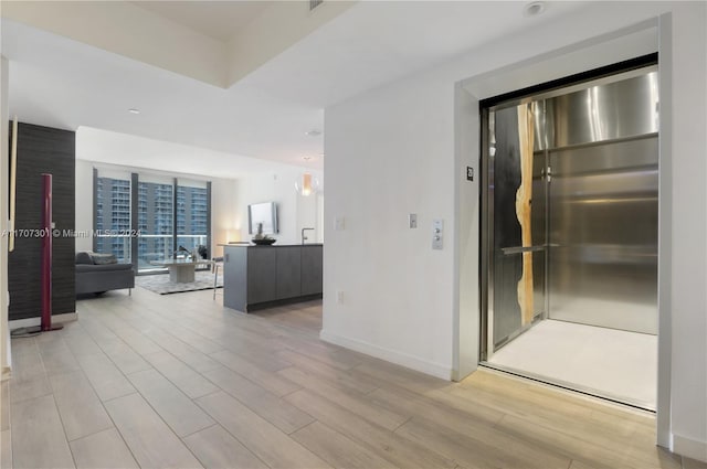 hall with elevator and light hardwood / wood-style floors