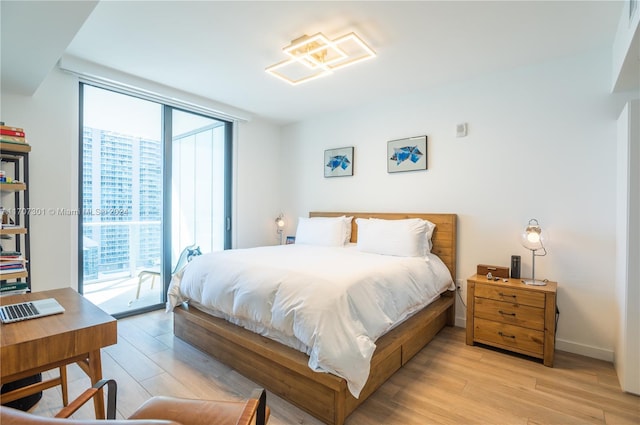 bedroom with access to exterior, light wood-type flooring, and multiple windows