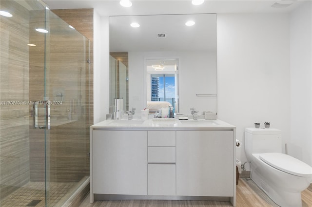 bathroom with hardwood / wood-style floors, toilet, an enclosed shower, and vanity