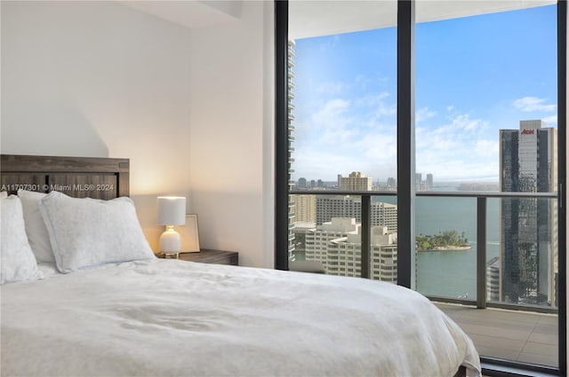 bedroom with floor to ceiling windows and a water view