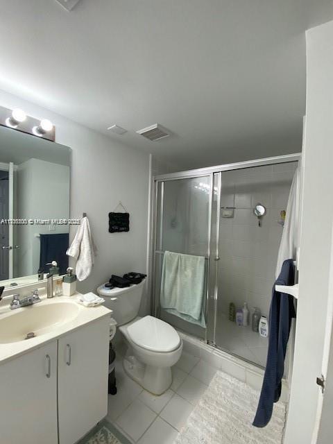 bathroom featuring vanity, tile patterned flooring, a shower with door, and toilet