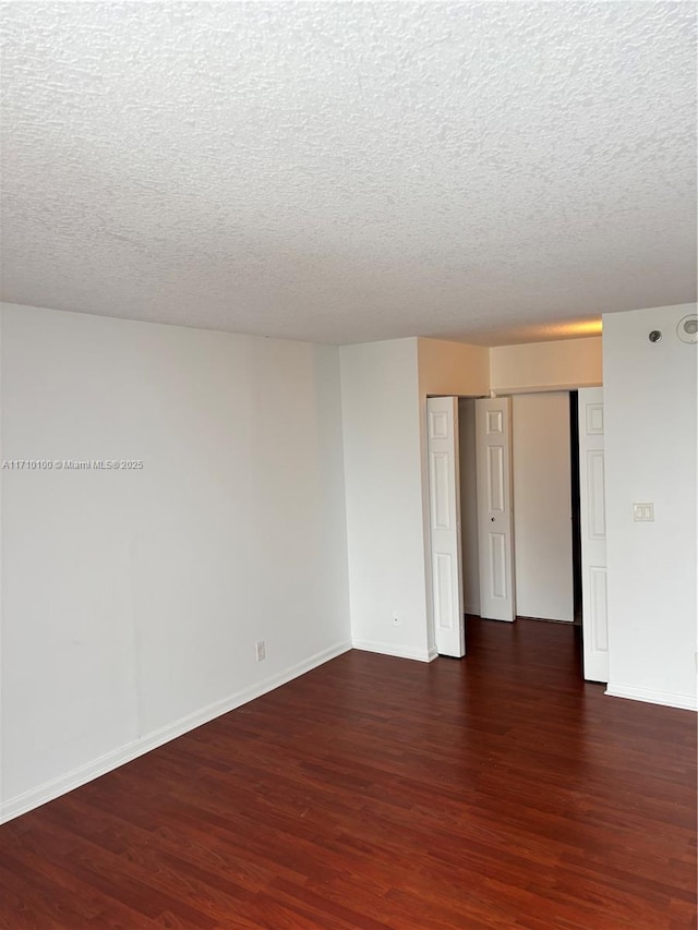 spare room featuring dark hardwood / wood-style flooring and a textured ceiling